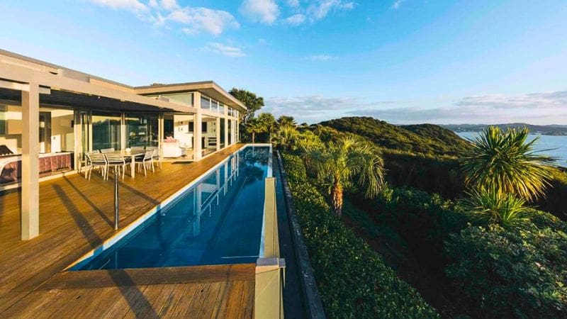 Infinity pool and modern architecture of a luxury lodge overlooking New Zealand's stunning coast.