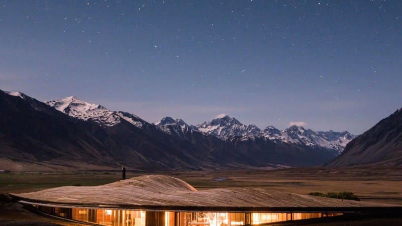 A stunning night sky over snow-capped mountains, perfect for stargazing from a luxury New Zealand lodge.
