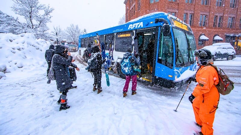 People boarding an RFTA bus in the snowy streets after doing top things to do in Aspen in the winter.