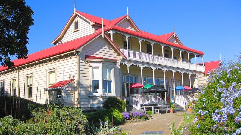 A colorful historic home with a red roof in Takapuna, one of the many interesting things to see and do in the area.