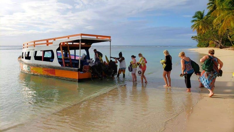 Tourists boarding a boat at a scenic beach, one of the popular tourist attractions in Trinidad and Tobago.