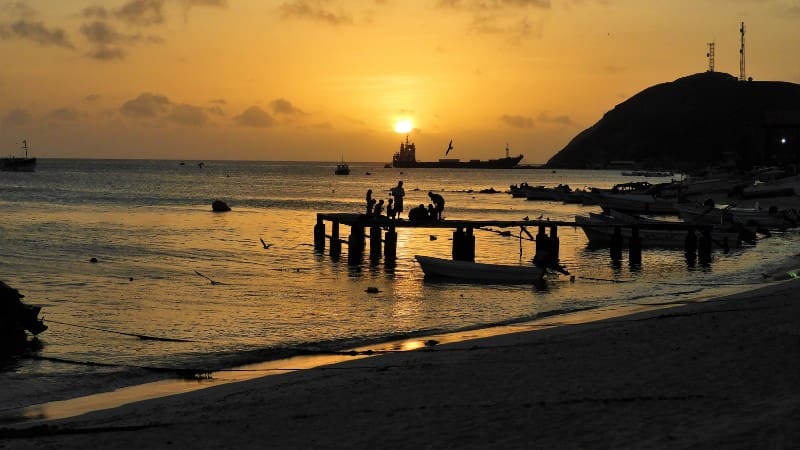 Tourists enjoying the sunset at a dock in Pigeon Point, one of the top tourist destinations in Tobago.