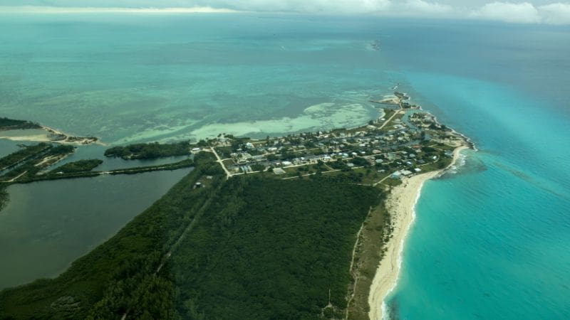 Aerial view of Bimini, Bahamas, showing a lush island split by waterways, bordered by sandy beaches and shallow turquoise waters.