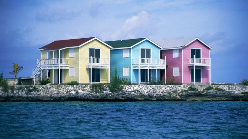 Colorful beachfront homes in pastel yellow, blue, and pink on New Providence Island, Bahamas, facing the sea.