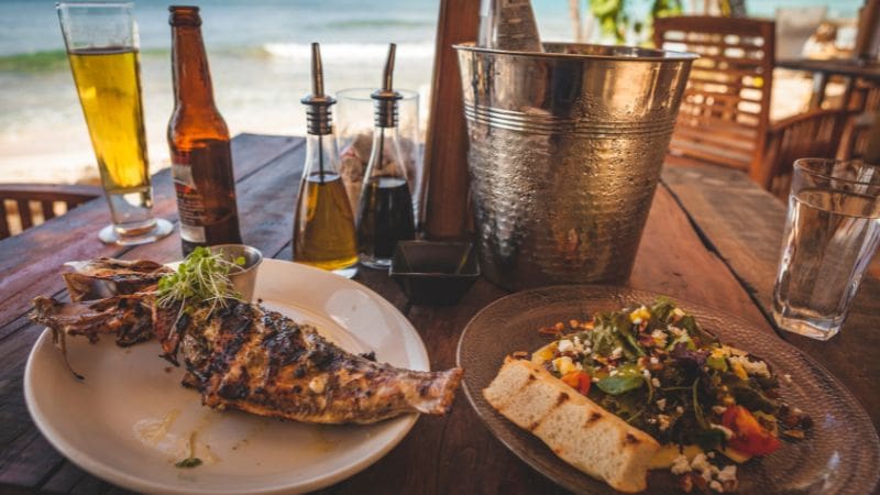 A table with local Bajan dishes and drinks, showcasing the affordable dining options when traveling to Barbados on a budget.