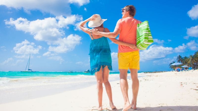 Couple embracing the sun and sand during their budget-friendly Barbados beach vacation.