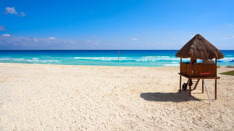 Sandy shores with a wooden hut overlooking the turquoise sea at Playa Marlin in Cancun.