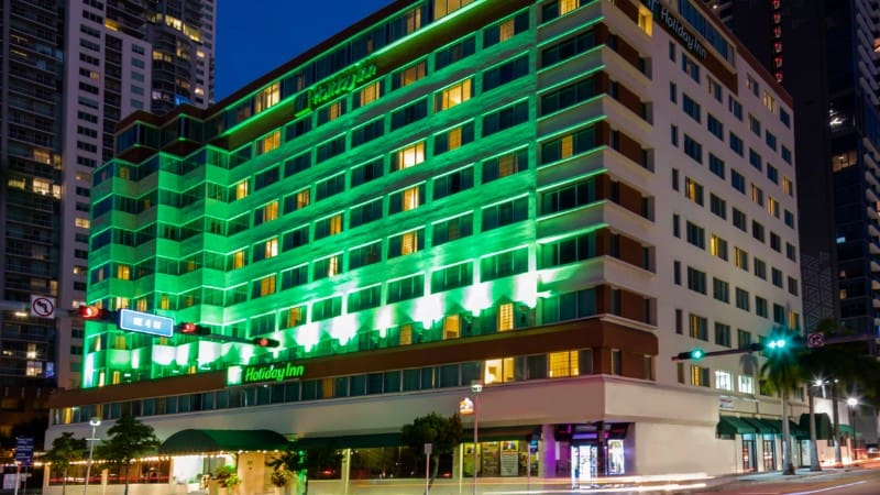 Holiday Inn Port of Miami with vibrant green lights, offers free cruise port shuttle.