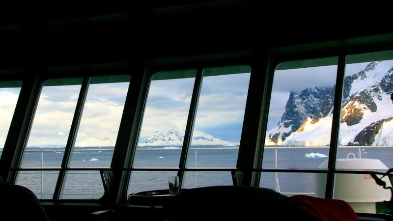 Enjoy scenic views from inside a luxury cruise ship navigating icy waters on your journey to Antarctica.