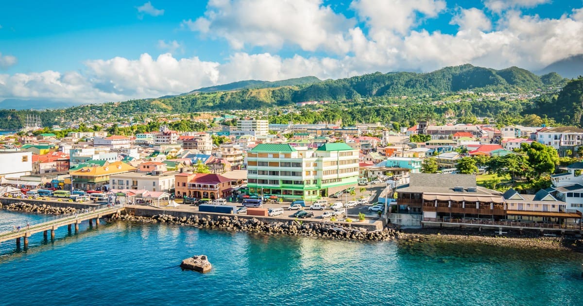 Living in Dominica offers stunning views of colorful houses, lush mountains, and the sea.