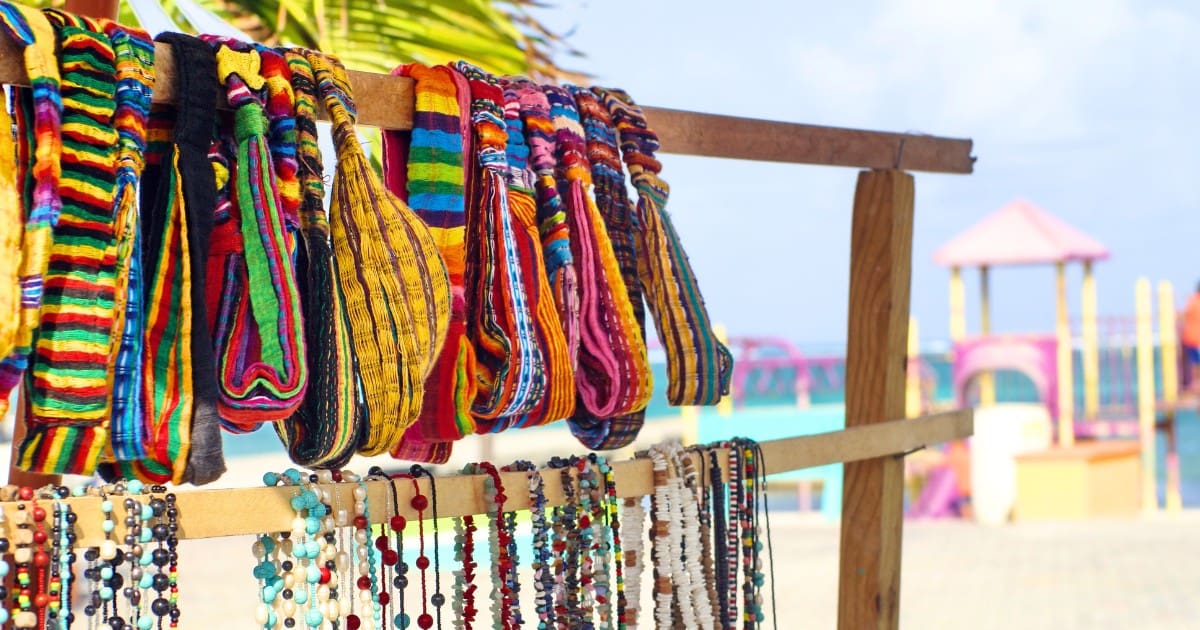 Colorful Belize souvenirs: handmade bags and jewelry on a beach stand.