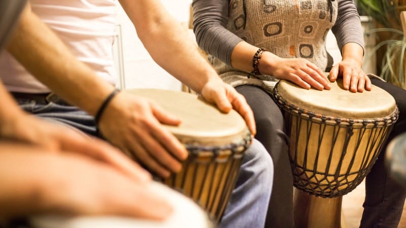 Hands playing traditional djembe drums, showcasing Belizean rhythms.