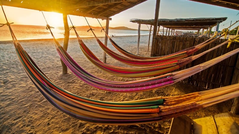 Colorful hammocks on a Belizean beach at sunset, popular souvenirs from Belize.