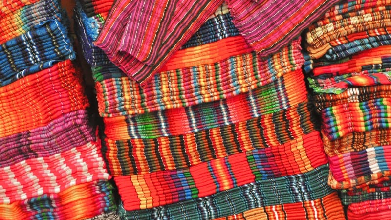 Handwoven textiles in bold patterns, displaying Belizean craftsmanship.